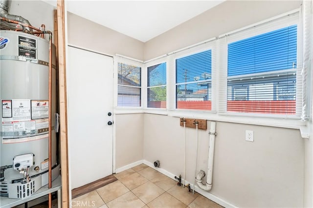 laundry room featuring light tile patterned floors and strapped water heater