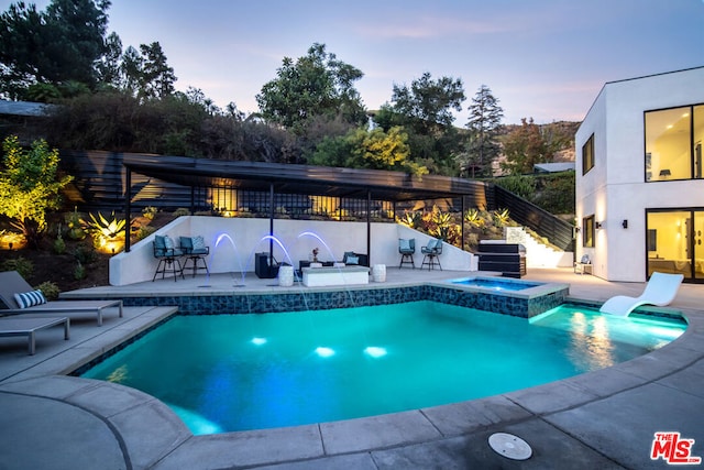 pool at dusk featuring a grill, an in ground hot tub, exterior bar, and a patio