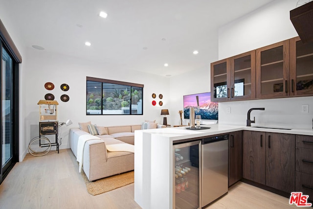 kitchen featuring kitchen peninsula, sink, dishwasher, light hardwood / wood-style floors, and wine cooler