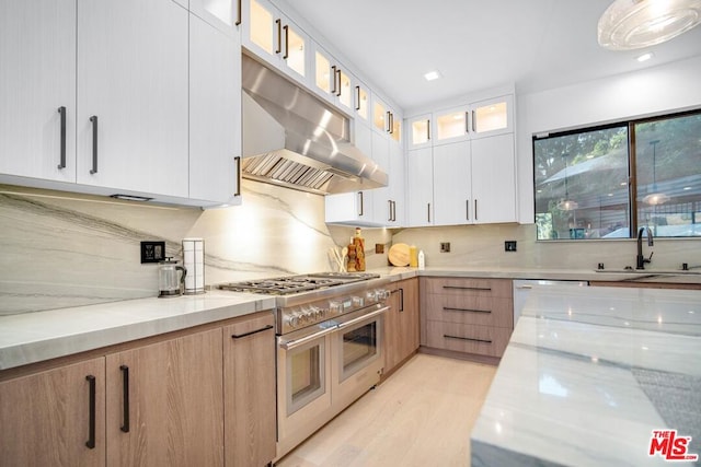 kitchen featuring light stone countertops, exhaust hood, sink, white cabinets, and light hardwood / wood-style floors