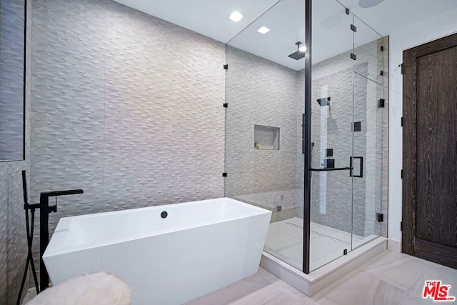 bathroom featuring separate shower and tub and tile walls