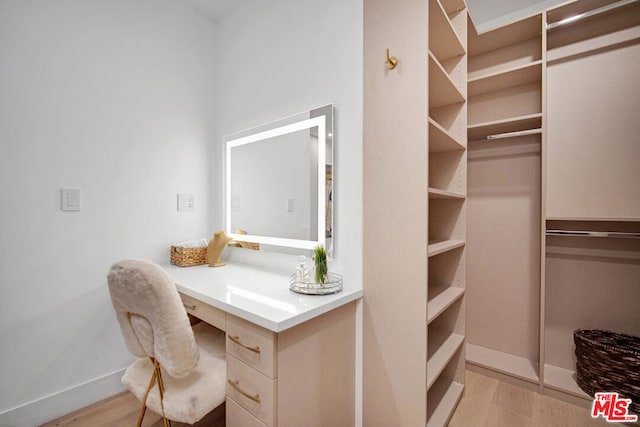 spacious closet with light hardwood / wood-style flooring and built in desk