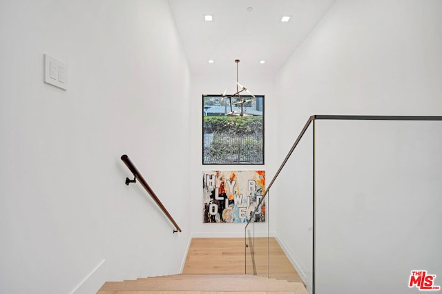 staircase featuring a chandelier, hardwood / wood-style flooring, and lofted ceiling