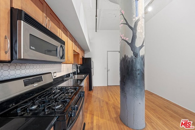 kitchen with decorative backsplash, stainless steel appliances, light hardwood / wood-style floors, and sink