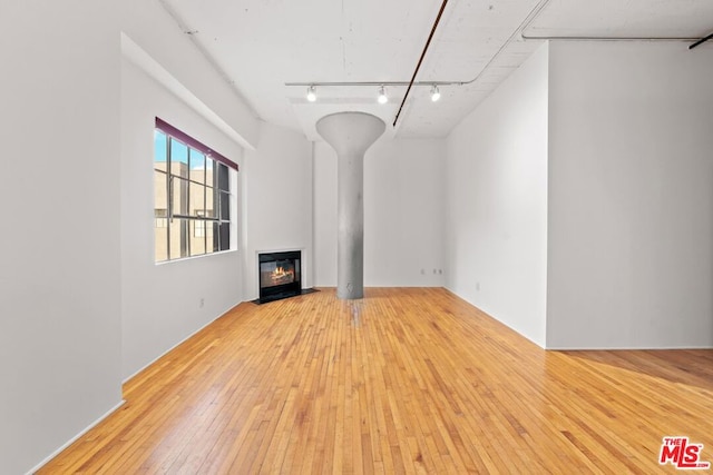 unfurnished living room with light hardwood / wood-style floors and rail lighting