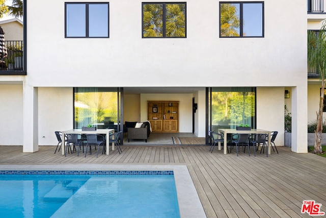 rear view of property featuring a pool side deck