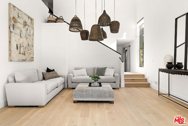 living room featuring a towering ceiling and light wood-type flooring