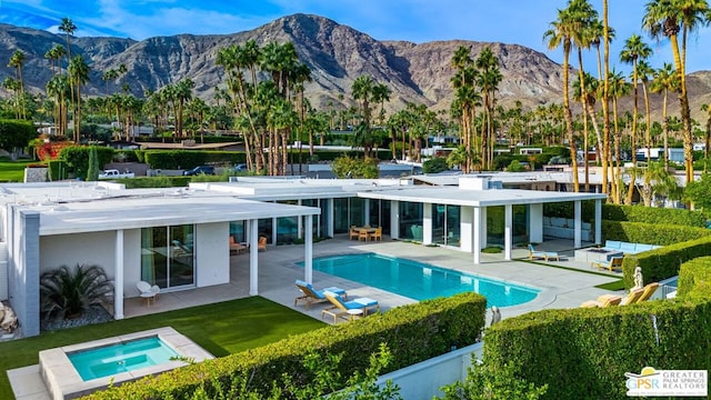 view of pool featuring a mountain view, a patio area, and an in ground hot tub