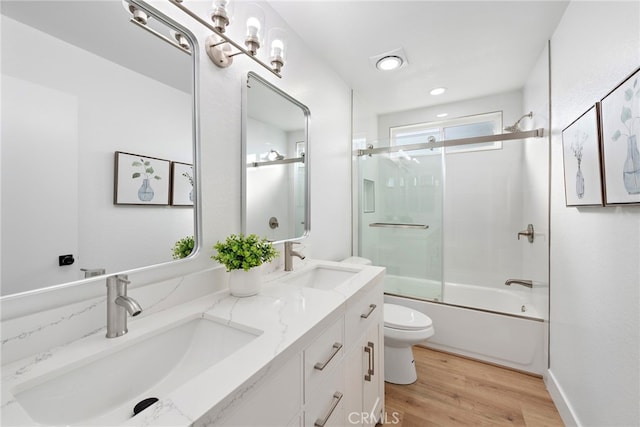 full bathroom with hardwood / wood-style floors, vanity, toilet, and shower / bath combination with glass door