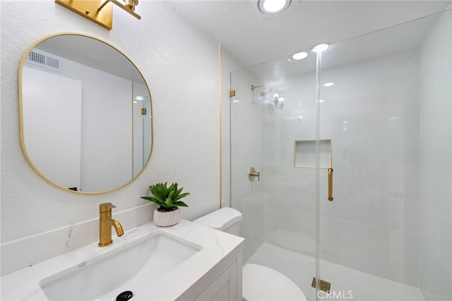 bathroom with vanity, toilet, and a shower with door