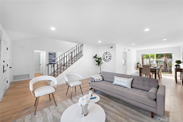 living room with light wood-type flooring and vaulted ceiling