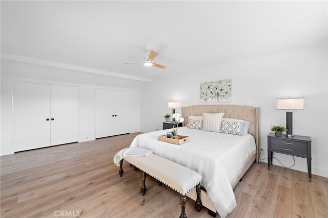 bedroom featuring ceiling fan, light wood-type flooring, and multiple closets