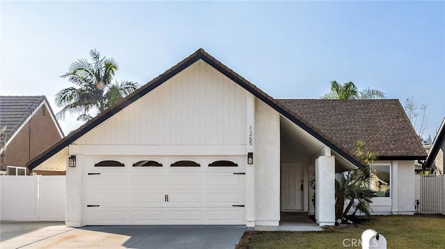 view of front of house featuring a shingled roof, fence, driveway, and an attached garage