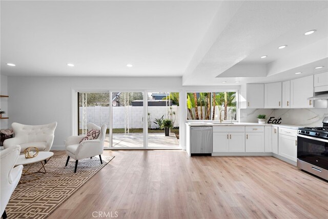 kitchen featuring sink, appliances with stainless steel finishes, tasteful backsplash, light hardwood / wood-style floors, and white cabinetry