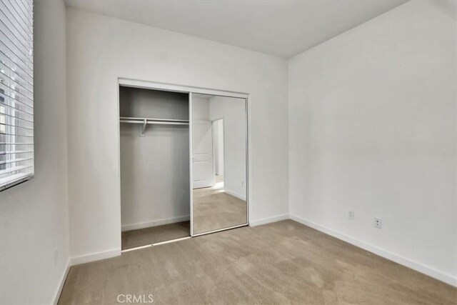 unfurnished bedroom featuring light carpet and a closet