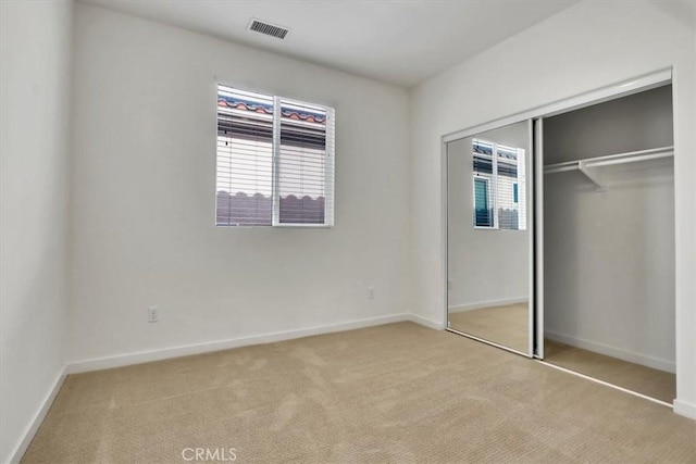 unfurnished bedroom featuring light carpet and a closet