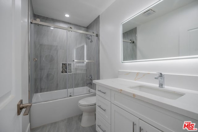 full bathroom with hardwood / wood-style flooring, toilet, vanity, and combined bath / shower with glass door