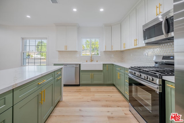 kitchen with sink, green cabinetry, appliances with stainless steel finishes, light hardwood / wood-style floors, and white cabinetry