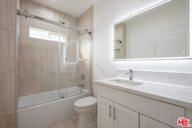 full bathroom featuring combined bath / shower with glass door, vanity, toilet, and tile patterned flooring