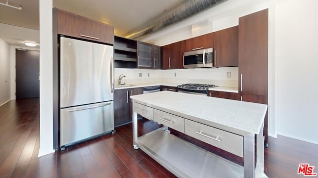 kitchen featuring appliances with stainless steel finishes, dark hardwood / wood-style flooring, a center island, and sink