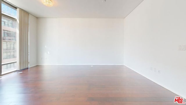 unfurnished room with a healthy amount of sunlight and dark hardwood / wood-style flooring