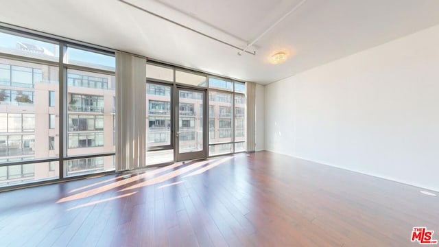 empty room with floor to ceiling windows and hardwood / wood-style flooring