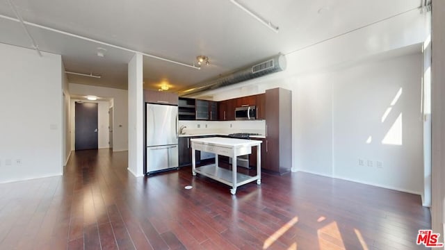 kitchen with dark brown cabinetry, a center island, dark wood-type flooring, and appliances with stainless steel finishes