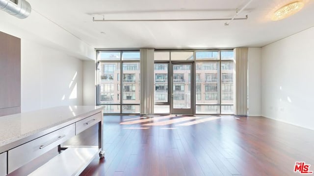 interior space with dark hardwood / wood-style floors, floor to ceiling windows, and rail lighting