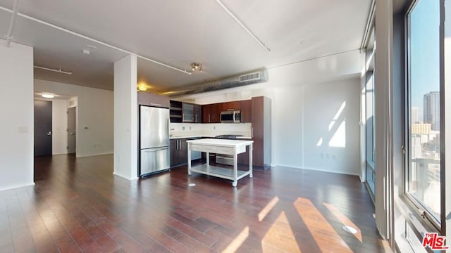 kitchen featuring a kitchen bar, dark wood-type flooring, a center island, and stainless steel appliances