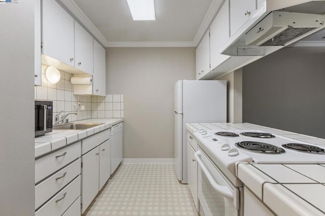 kitchen featuring white appliances, backsplash, white cabinets, sink, and tile counters