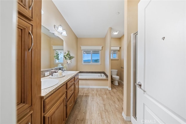 bathroom featuring a tub, hardwood / wood-style flooring, vanity, and toilet