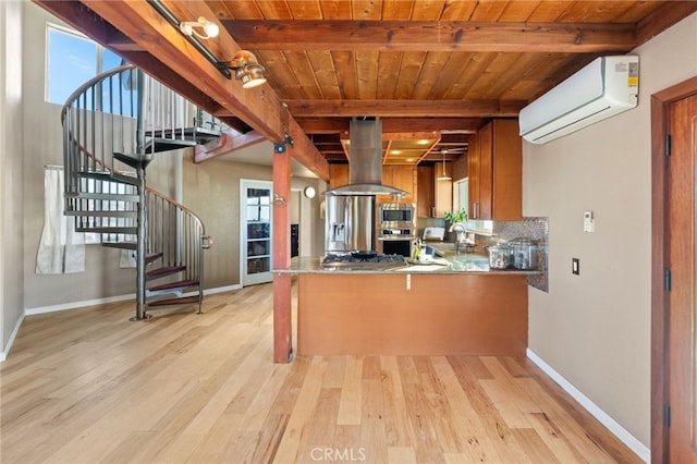 kitchen featuring appliances with stainless steel finishes, island exhaust hood, a wall mounted AC, beamed ceiling, and kitchen peninsula