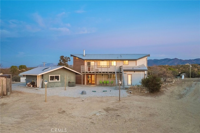 back house at dusk with a deck with mountain view and a garage