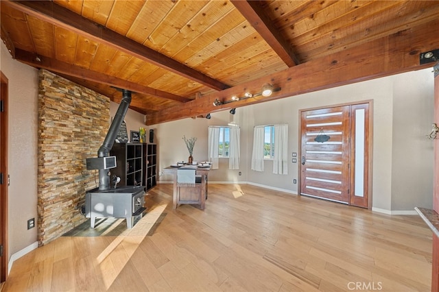 interior space with a wood stove, light hardwood / wood-style flooring, beamed ceiling, and wooden ceiling