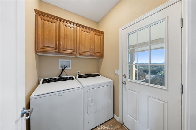 clothes washing area with washing machine and clothes dryer and cabinets