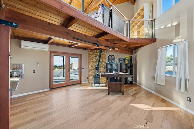 interior space with beam ceiling, light hardwood / wood-style flooring, an AC wall unit, and a healthy amount of sunlight