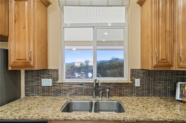 kitchen featuring sink, light stone countertops, and tasteful backsplash