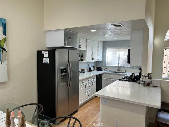 kitchen with light hardwood / wood-style floors, kitchen peninsula, sink, stainless steel appliances, and white cabinets