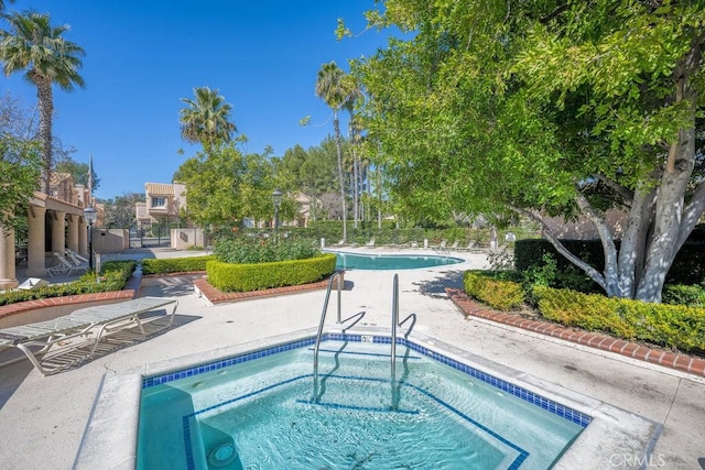 community pool with a community hot tub, fence, and a patio