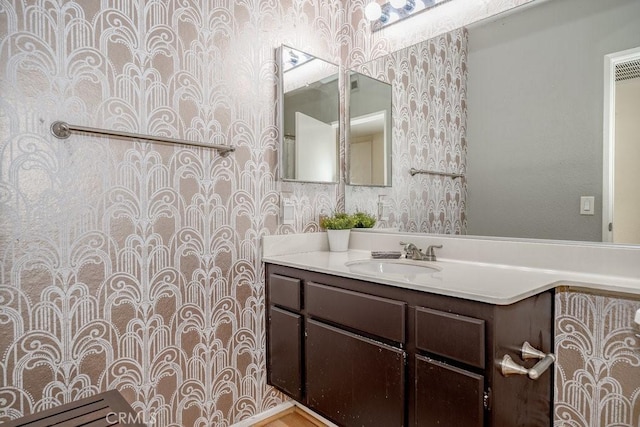 bathroom featuring vanity and wallpapered walls