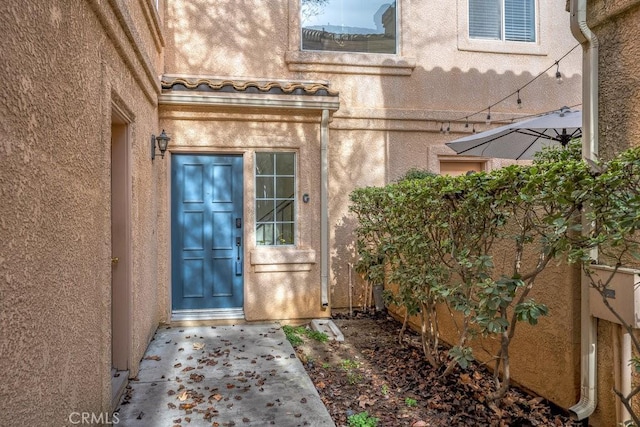 entrance to property featuring a tile roof and stucco siding