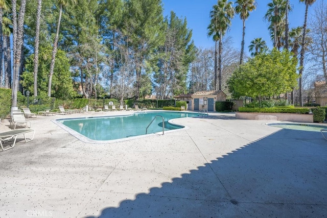 community pool with a patio area and fence