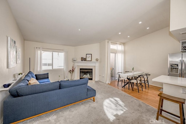 living room with light wood-style flooring, visible vents, a tiled fireplace, and recessed lighting