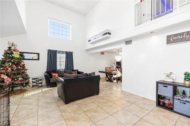 living room featuring a notable chandelier, plenty of natural light, light tile patterned flooring, and a towering ceiling