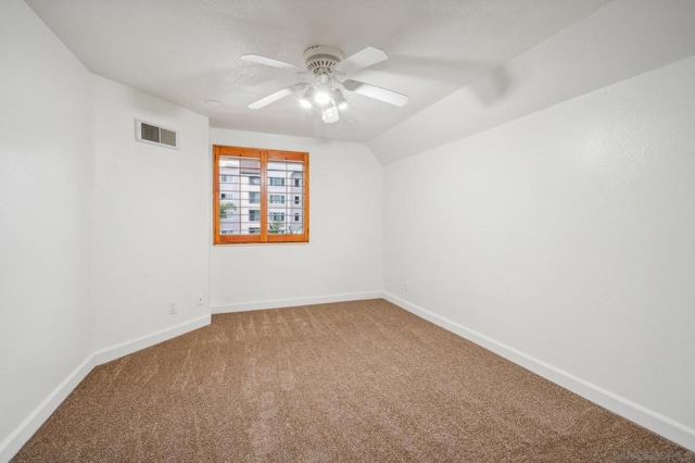 carpeted spare room featuring ceiling fan and lofted ceiling