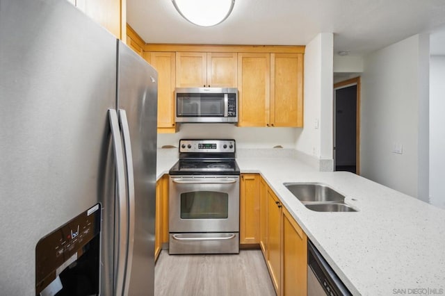 kitchen featuring sink, light brown cabinets, light stone counters, light hardwood / wood-style flooring, and appliances with stainless steel finishes