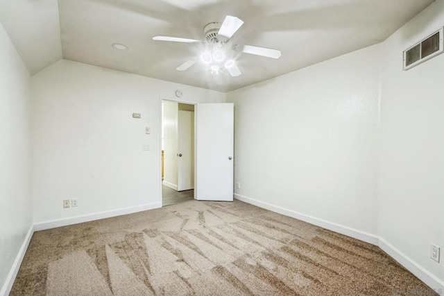 carpeted spare room featuring ceiling fan and vaulted ceiling