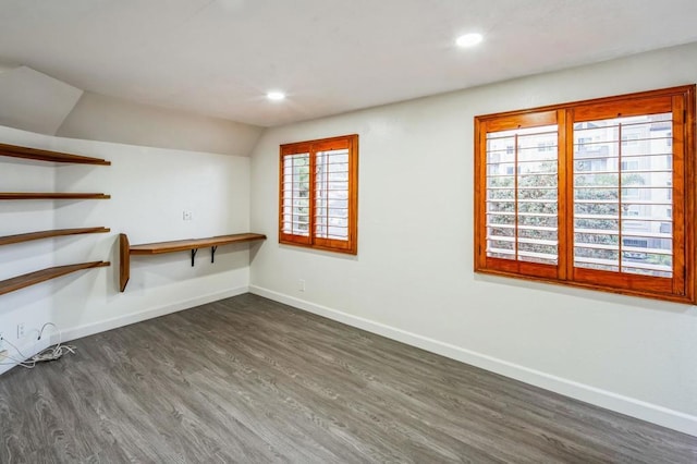 unfurnished room with lofted ceiling, dark hardwood / wood-style flooring, built in desk, and a wealth of natural light