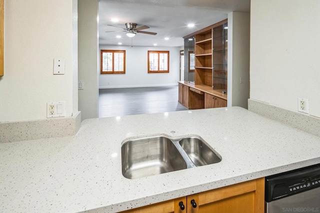 kitchen featuring light stone countertops, ceiling fan, sink, dishwasher, and hardwood / wood-style floors