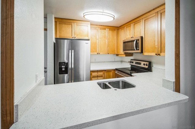 kitchen with kitchen peninsula, light brown cabinets, a textured ceiling, and stainless steel appliances